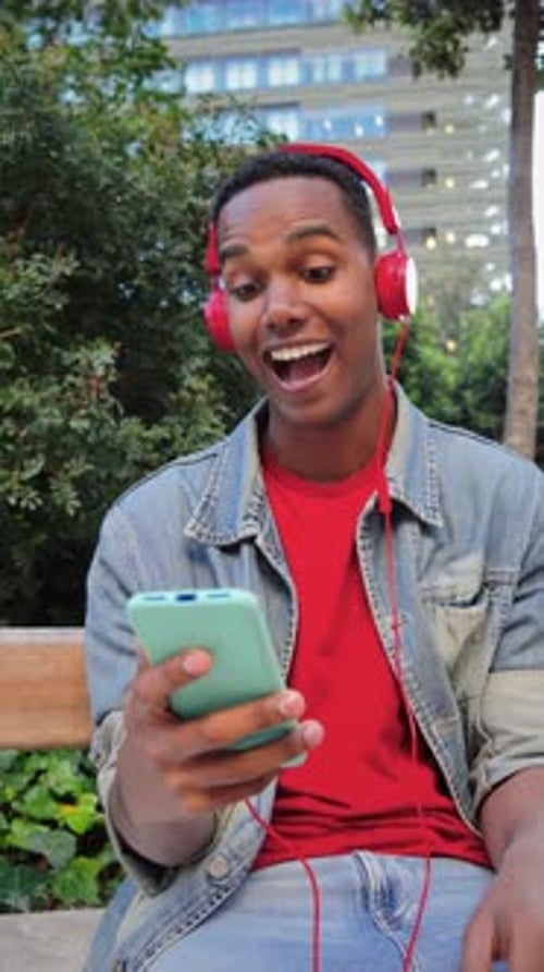 Smiling Young Adult Using Smartphone in Urban Park