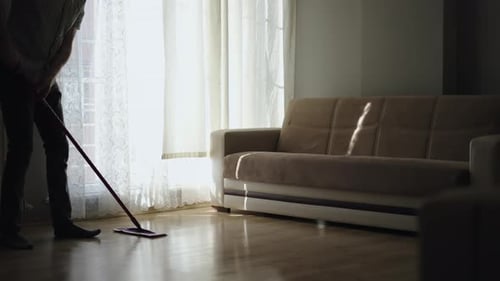 Adult Cleaning Floor in Brightly Lit Living Room