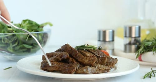 Woman eating delicious beef meat at white table, closeup
