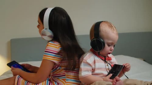 Children Listening to Music with Headphones on Bed
