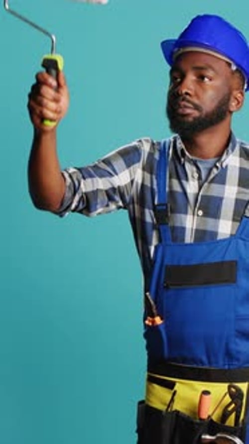 Vertical Video Repairman in Overalls Painting Walls with Roller Brush