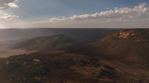 Rising aerial offers panoramic view of barren hilly desert landscape