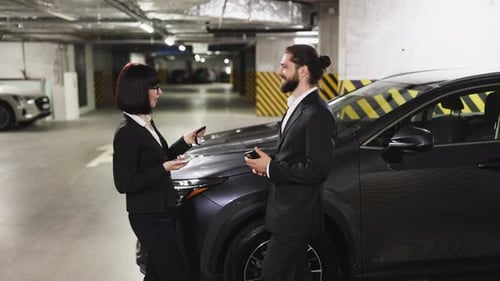 Businesswoman Handing Car Keys to Man in an Underground Parking Lot