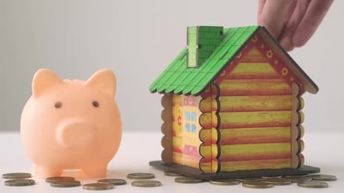 Hand is Putting Coin in Piggy Bank