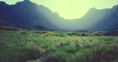 Majestic Mountains Surround a Serene Green Valley at Sunrise