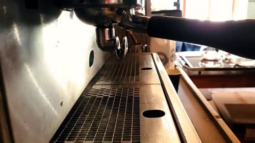 Close up view of chrome espresso pouring steaming hot double shot coffee into glass cups.