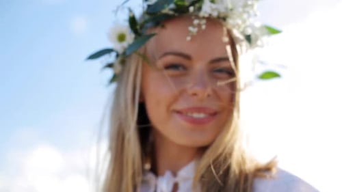 Smiling woman wears flower crown close up on blue sky