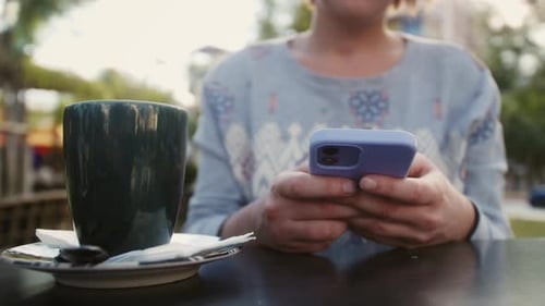 Woman Uses Phone While Sitting in Cafe