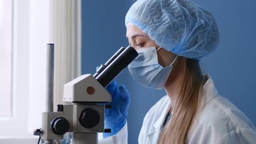 Female Scientist Viewing Sample Under Microscope in Laboratory