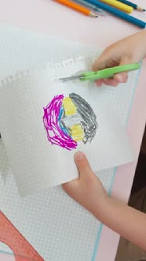 Child Cuts Perforated Edge of Sketchbook Page with Picture