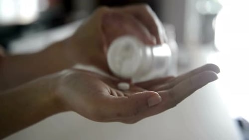 Hand eines unbekannten Patienten, der Medikamente einnimmt. Pillen und Medikamente in die Handfläche gießen