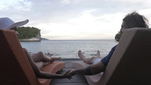 4k video footage of a young couple relaxing on deckchairs while overlooking the ocean