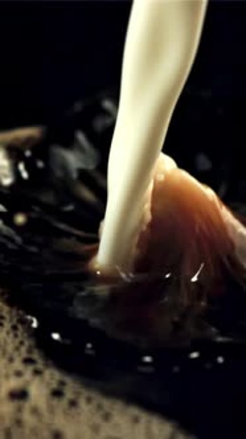 A Stream of Milk Pours Into the Black coffeeFilmed is Slow Motion 1000 Frames Per Second