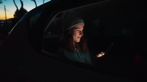 Young Woman Using Phone in Car at Night