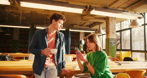Young Students Sharing Information on Smartphone in University Library