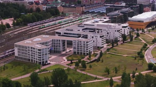 Slide and Pan Shot of Modern Design Apartment Buildings and Green Park Near Railway Tracks and Train