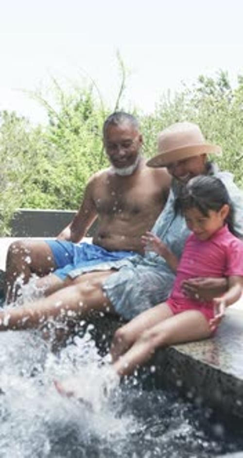 Vertical video: Splashing water, grandparents and child enjoying time together by pool