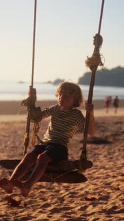 Young Boy Enjoying A Swing Ride With Soft Sunset Hues