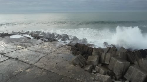 Waves Crashing Against Rocky Coastline on Cloudy Day