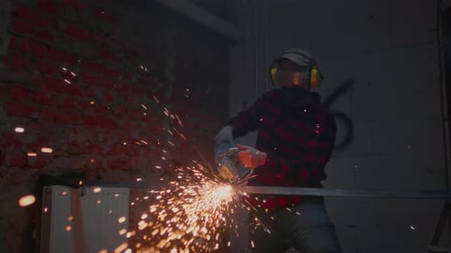 Man Industrial Worker or Construction Worker Cuts Metal with a Angle Grinder Manufacturing Plant
