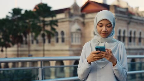 Woman in Hijab Using Smartphone in Urban Setting