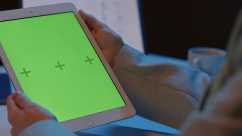 Frau hält Tablet mit grünem Bildschirm in der Hand