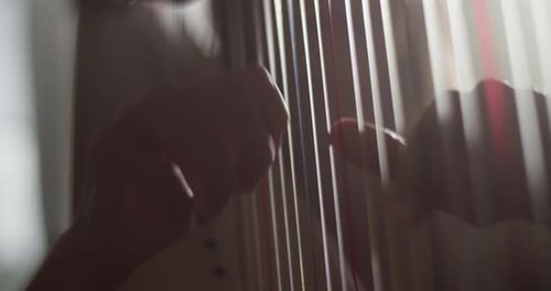 Hands Playing Strings of a Harp Instrument