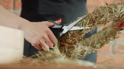 Woman Shaping Holiday Wreath with Scissors in Studio