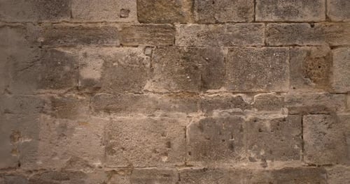 Close-up of an old medieval stone porous facade wall. Static 4K shot