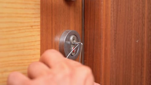 Hand with master key breaks into wooden door, open locked lock Insurance robbery