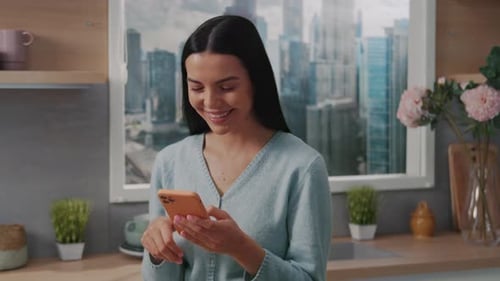 Woman Smiling Using Smartphone in Modern Kitchen