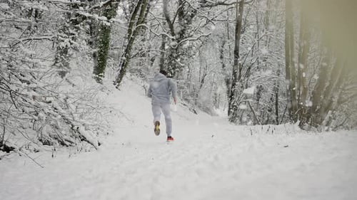 Man Running in Snowy Winter Forest Landscape