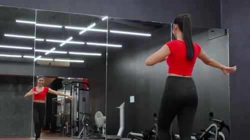 Beautiful young asian woman dancing ballet near mirror for workout with cardio in fitness gym.