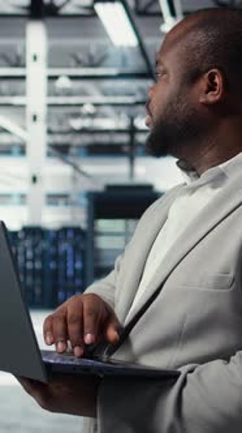 Ingénieur Vidéo vertical dans un centre de données utilisant un ordinateur portable pour mettre à jour les baies de stockage