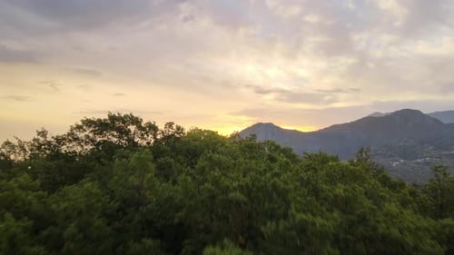 Beautiful aerial forwarding shot of sunrise over a scenic mountain range with the view of a small to