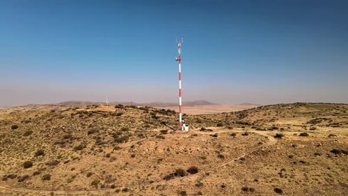 Large telecommunications tower on top of a remote mountain, accessed by a dirt road, showcasing the