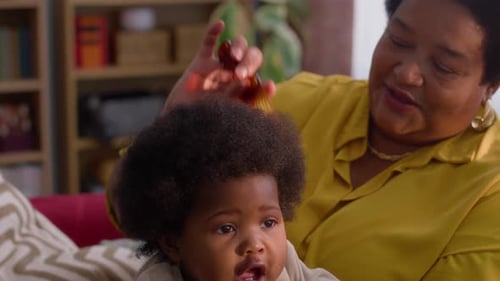 Woman Combs Infant's Curly Hair Indoors