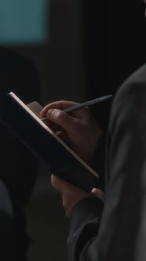 Vertikale der Hände des Teilnehmers, der sich während der Konferenzrede Notizen macht