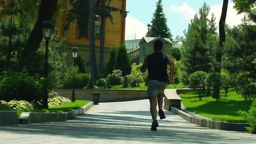 Man running away in slow motion on park alley for fitness and healthy lifestyle