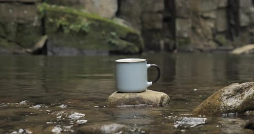 Ein Becher auf einem Stein in der Nähe eines Feuers am Flussufer