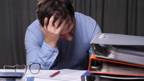 Stressed Businessman Holding His Head with His Hand at Office Desk