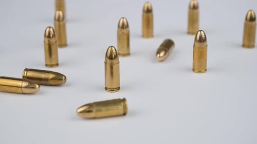 Shiny Golden Bullets Scattered on White Surface