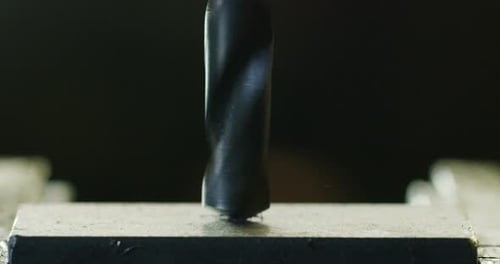 Macro shot of a drill that pierces a sheet of iron or steel. The tip of the metal drill with a cir