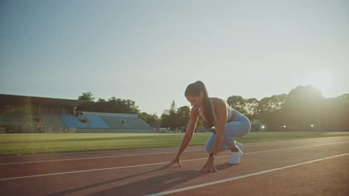 Beautiful Fitness Woman in Light Blue Athletic Top and Leggings is Starting a Sprint Run in an Outd