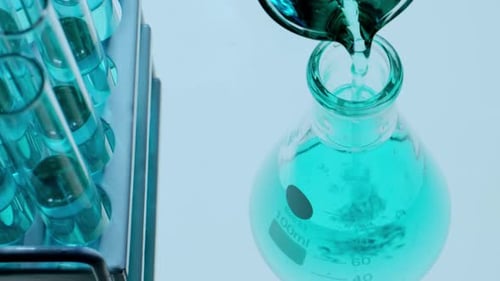 Gros plan du versement d'une solution chimique bleue dans une fiole Erlenmeyer en laboratoire