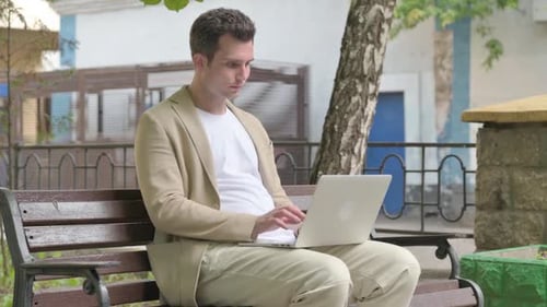 Young Man Working on Laptop Rubbing Neck