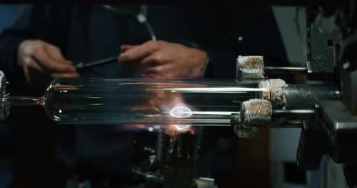 Slow motion macro of glass blower working with flame on a handmade art piece of glass from preciou