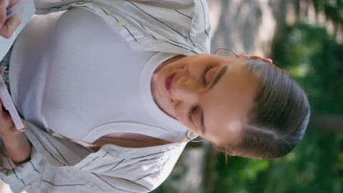 Beautiful Woman Creating Text to Notepad in Park with Mobile Close Up Vertically