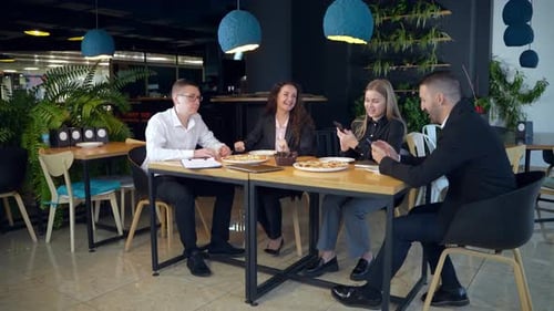 Office team sitting at the table in a café and talking.