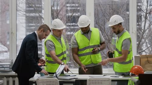 Construction Team and Engineer Reviewing Renovation Plan at Office